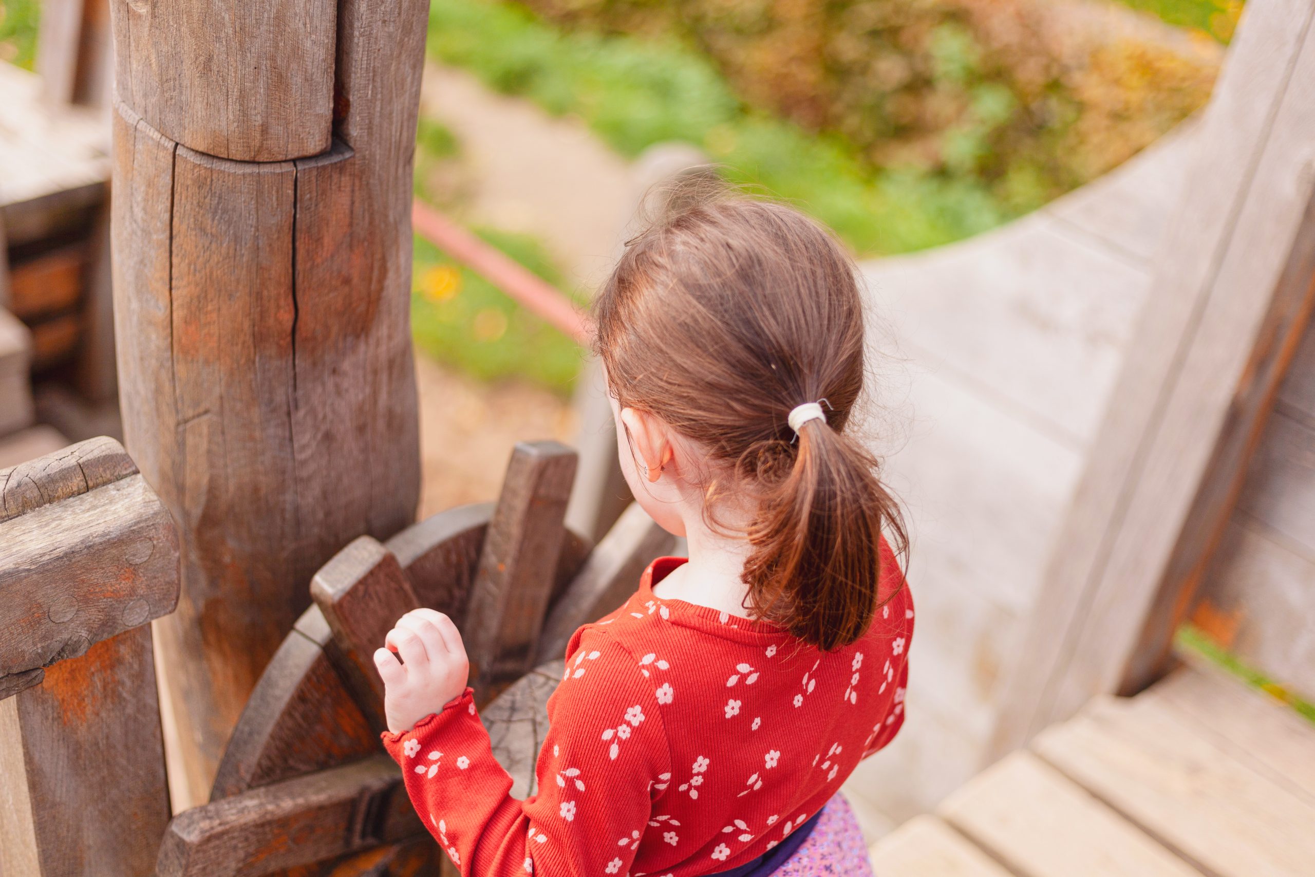 little girl in a red T-shirt plays on the playground on a pirate ship